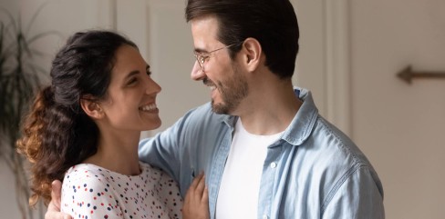 תמונה של המאמר מה חשוב בזוגיות המציגה זוג מחייך ומחובק המביט אחד בשני במבט אוהב בחלל ביתם.