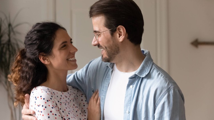 תמונה של המאמר מה חשוב בזוגיות המציגה זוג מחייך ומחובק המביט אחד בשני במבט אוהב בחלל ביתם.