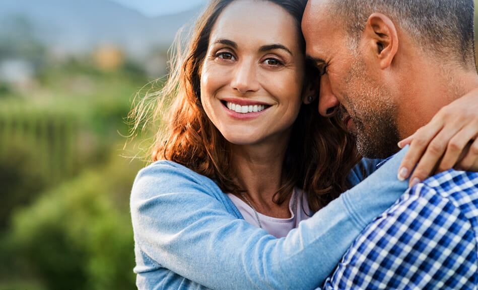 תמונת אווירה מדף הבית של אורית צוקר יועצת זוגית מציגה זוג מחובק במרחב פתוח כשהאישה מביטה ישר למצלמה ומחייכת.